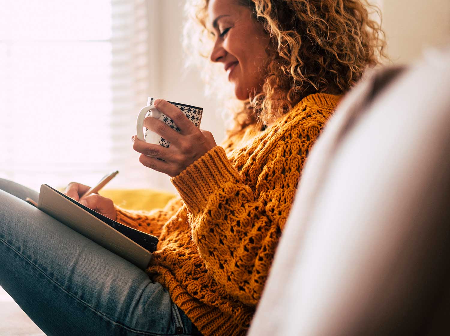 Woman journaling (one of the best manifesting methods and techniques) while drinking coffee