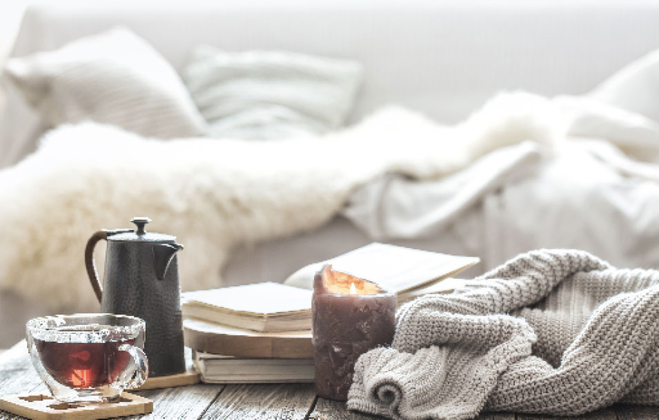 Tea on a table with a journal and blanket in the background are used to create a sacred space in a daily ritual for manifesting