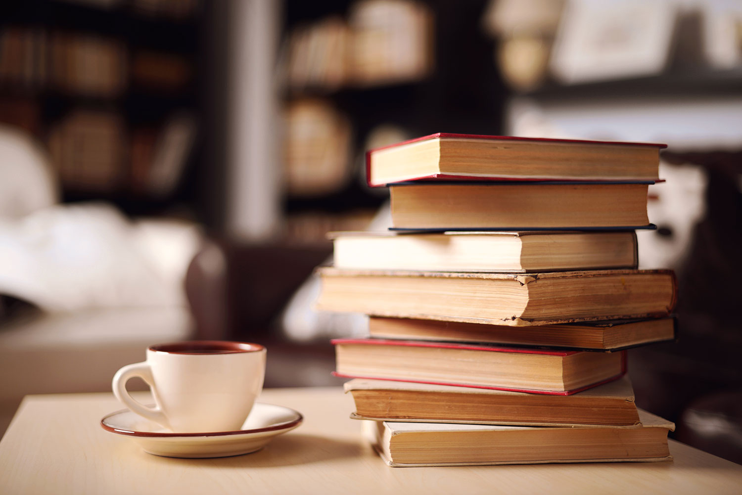 Stack of books about manifesting on a table with a coffee cup